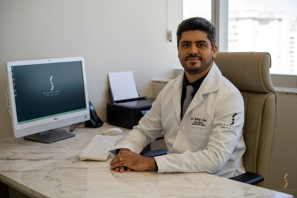 Dr. Rodrigo Lima, urologista da Singulari Medical Team, posando sentado em seu consultório